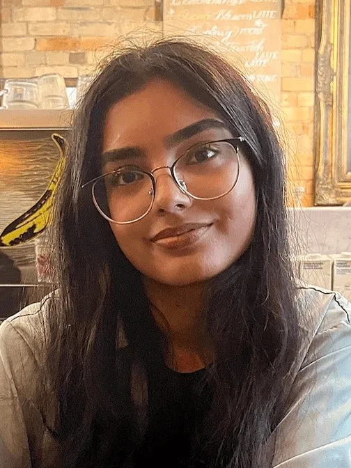 Iman Syed smiling, wearing glasses, indoors
